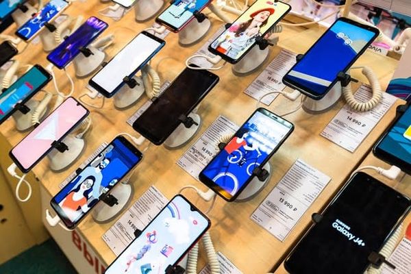 Diversos modelos de smartphones expostos em suportes de segurança em uma prateleira de loja de varejo.