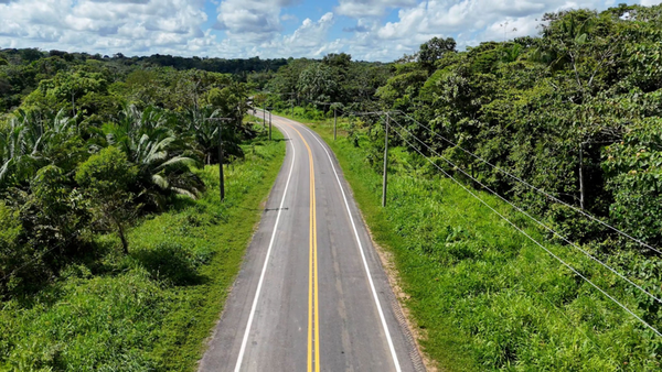 Trecho asfaltado da rodovia BR-307 cercado por vegetação amazônica sob céu com nuvens, no Amazonas.