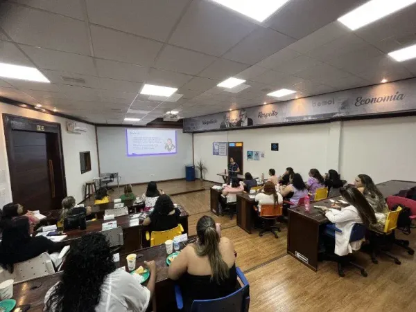 Mulheres sentadas em bancadas assistem a uma palestra em sala de aula com projeção da Bemol, em Manaus.
