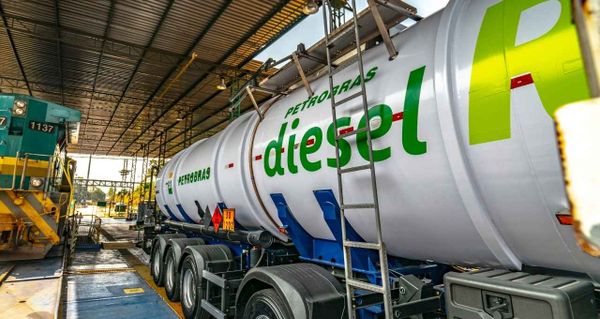 Caminhão-tanque branco da Petrobras com a inscrição diesel em verde estacionado em um terminal de carregamento.