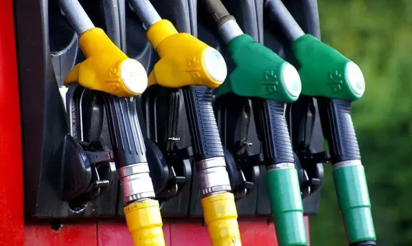 Bicos de bombas de combustível em um posto, com cores amarela e verde em destaque.