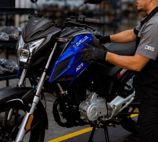 Colaborador com uniforme da DBS manuseia motocicleta azul e preta do modelo AZ170 Bravo da marca Avelloz em Manaus.