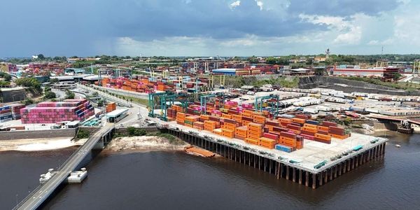 Pátio do terminal portuário Super Terminais em Manaus com centenas de contêineres coloridos empilhados à beira do Rio Negro.