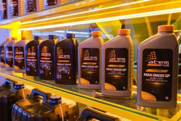 Frascos de lubrificantes das linhas Torque e Max da marca Atem Lub expostos em uma prateleira iluminada.