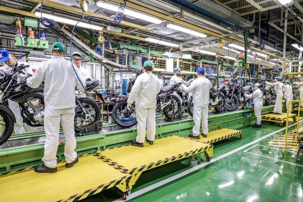 Colaboradores com uniformes brancos trabalham na linha de montagem de motocicletas na fábrica da Honda em Manaus.
