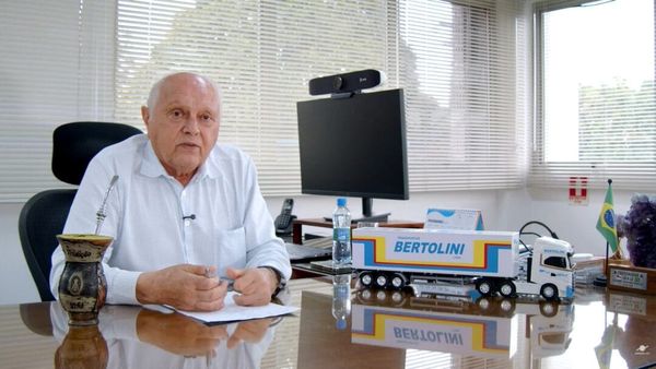 Irani Bertolini, presidente da Fetramaz, sentado à mesa de seu escritório com uma miniatura de caminhão da transportadora.