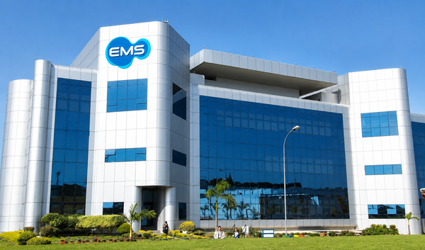 Fachada moderna do prédio da EMS com vidros azuis e logotipo da empresa em destaque sob céu limpo.
