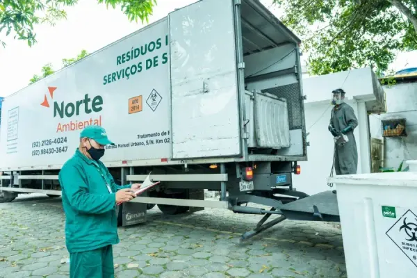 Funcionários da Norte Ambiental operam caminhão de coleta de resíduos industriais e de serviços de saúde.