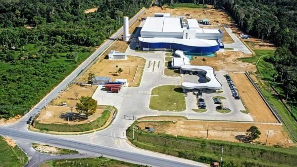 Vista aérea da fábrica da Novamed no Polo Industrial de Manaus, destacando a estrutura branca e azul cercada por vegetação.
