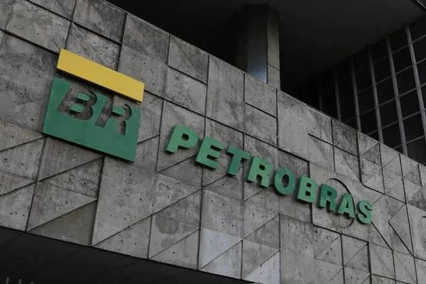 Logotipo da Petrobras em letras verdes e amarelas fixado em uma parede de concreto com texturas triangulares.