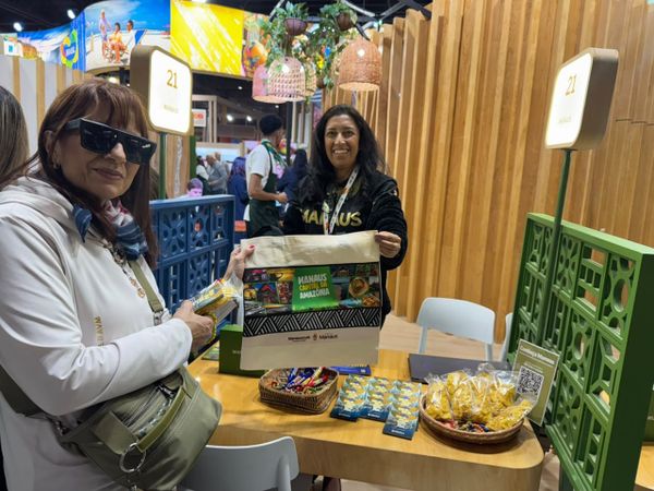 Mulheres seguram sacola com a frase Manaus Capital da Amazônia em estande na Feira Internacional de Turismo, na Argentina.