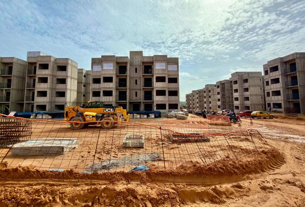 Canteiro de obras com prédios residenciais em construção e uma máquina carregadeira amarela da marca JCB em Manaus.