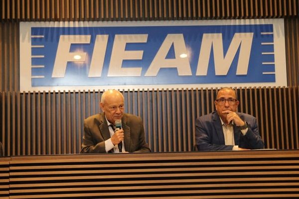 O presidente da Fieam, Antonio Silva, fala ao microfone sentado à mesa ao lado de outro representante da federação.