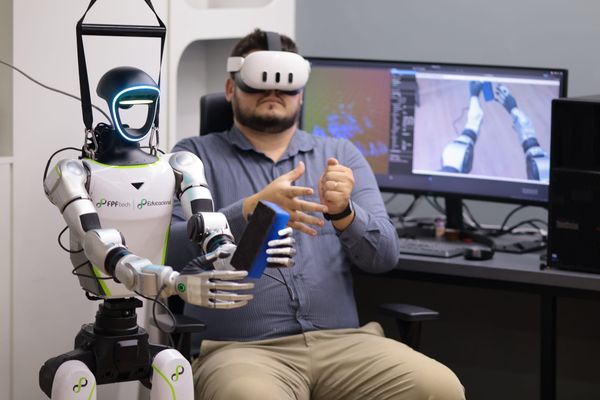 Pesquisador com headset de realidade virtual opera robô humanoide Unitree G1 em laboratório da FPFtech em Manaus.