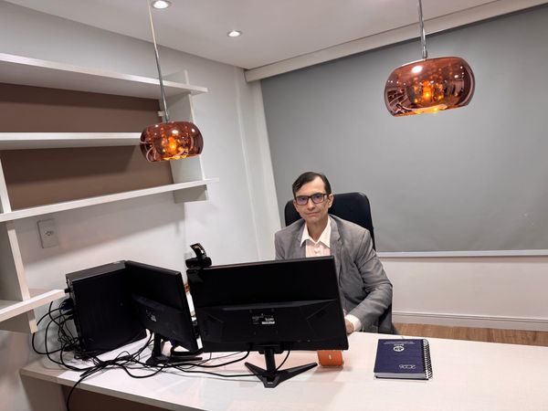 Roberto Nogueira, especialista em direito bancário, sentado em seu escritório em frente a dois monitores de computador.