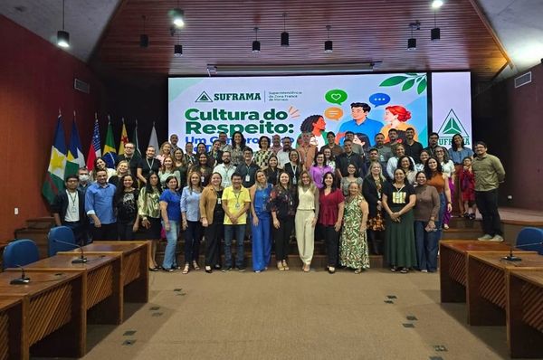 Grupo de servidores da Suframa posa para foto no auditório da autarquia em Manaus, à frente de telão com o tema Cultura do Respeito.