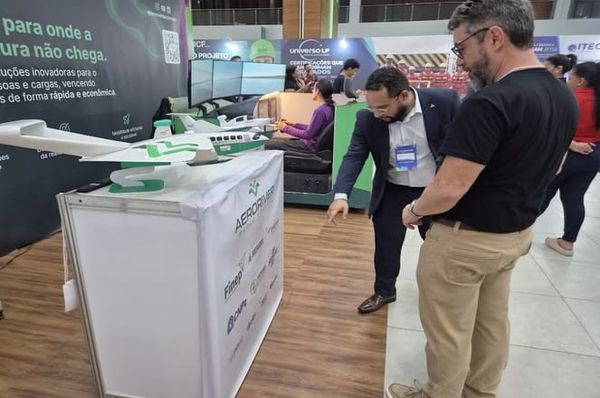 Homens observam maquete de aeronave da AeroRiver em estande durante o 2º Cenatec, no Centro de Convenções Vasco Vasques.