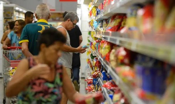 Consumidores circulam em corredor de supermercado observando produtos nas prateleiras em Manaus.