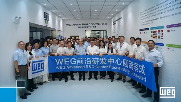 Executivos e colaboradores da WEG seguram faixa azul celebrando a inauguração do Centro Avançado de P&D em Wuxi, na China.