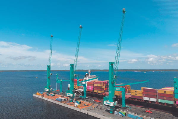 Guindastes verdes operando em píer flutuante do Super Terminais durante movimentação de navio de contêineres em Manaus.