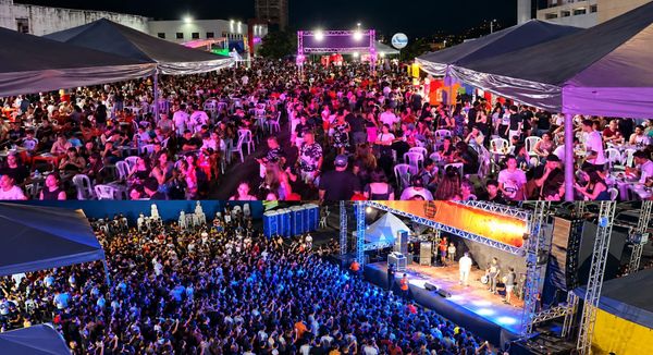 Público reunido em mesas sob tendas e multidão acompanhando show em palco iluminado durante evento noturno em Manaus.