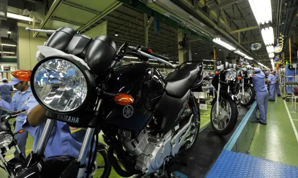 Linha de montagem de motocicletas da Yamaha no Polo Industrial de Manaus, com trabalhadores uniformizados em azul.