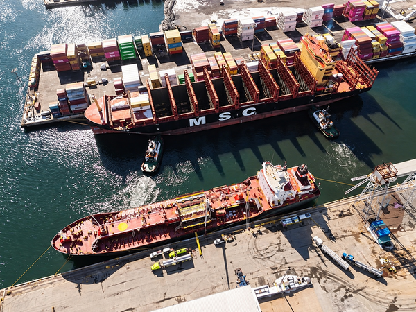 Navio porta-contêineres da MSC atracado em terminal portuário com diversos contêineres coloridos empilhados ao fundo.