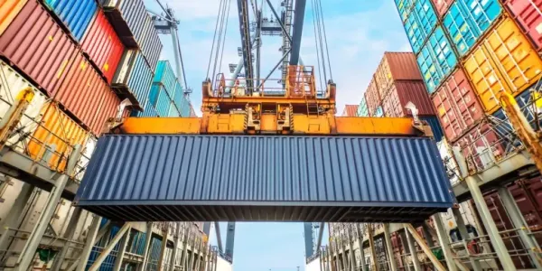 Guindaste portuário içando um contêiner azul em meio a pilhas de contêineres coloridos em um terminal de carga.