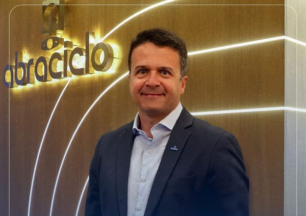 O executivo Ronaldo Ribeiro sorri em frente ao logotipo iluminado da Abraciclo.