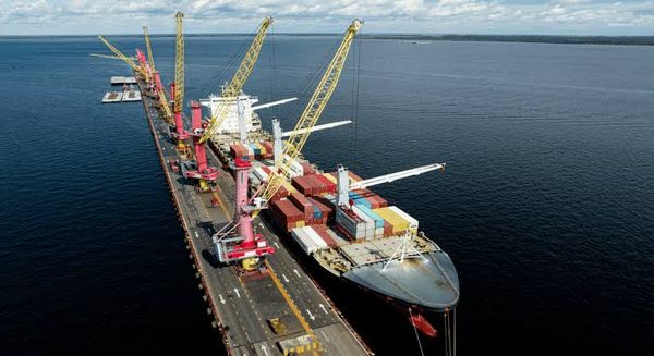 Navio porta-contêineres atracado em terminal portuário com guindastes operando o carregamento de cargas em Manaus.