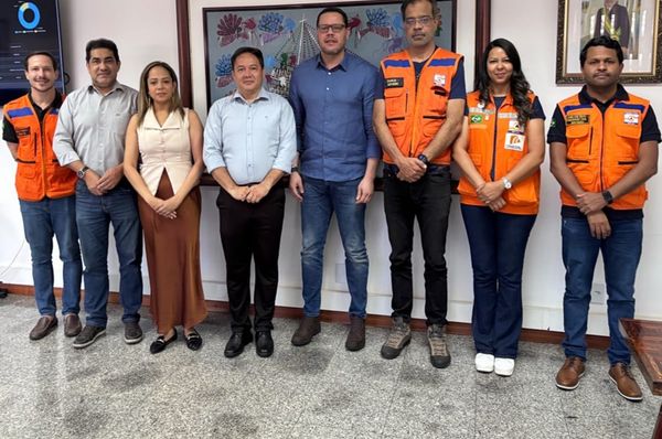 Representantes de órgãos federais e do Amazonas posam para foto na Suframa, alguns vestindo coletes laranjas da Defesa Civil.