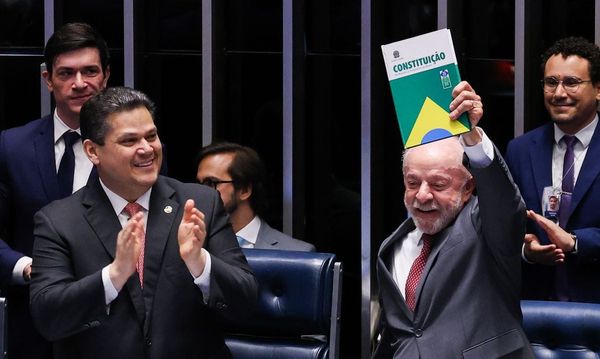 O presidente Lula levanta um exemplar da Constituição Brasileira ao lado de parlamentares no Congresso Nacional.