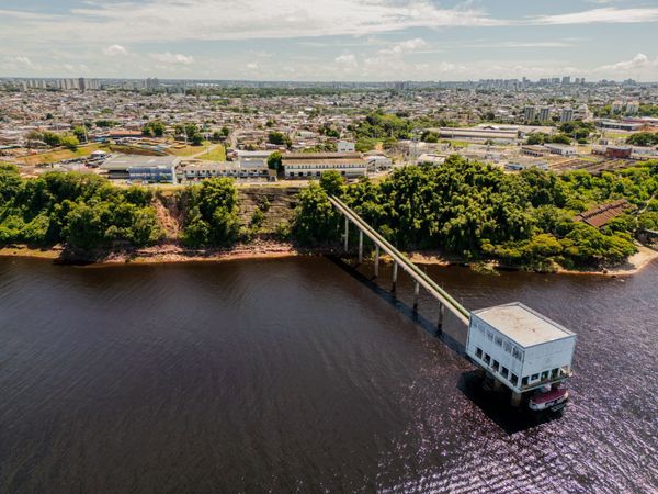 Vista aérea da estação de captação de água da Águas de Manaus avançando sobre as águas escuras do Rio Negro.