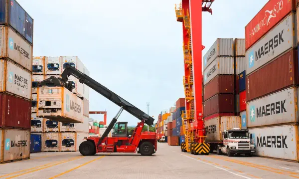 Empilhadeira de longo alcance movimenta contêineres da Maersk em terminal logístico.