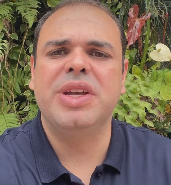 O governador do Amazonas, Roberto Cidade, fala em vídeo com fundo de folhagens verdes e flores.