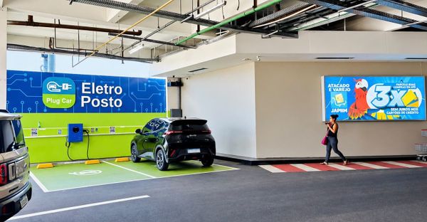 Carro elétrico preto estacionado em vaga de recarga com painel escrito Eletro Posto em unidade do Grupo DB em Manaus.