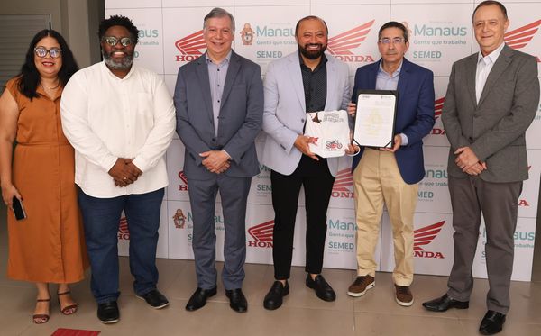 Seis representantes da Honda e da Prefeitura de Manaus posam para foto segurando o termo de cooperação e uma camiseta.