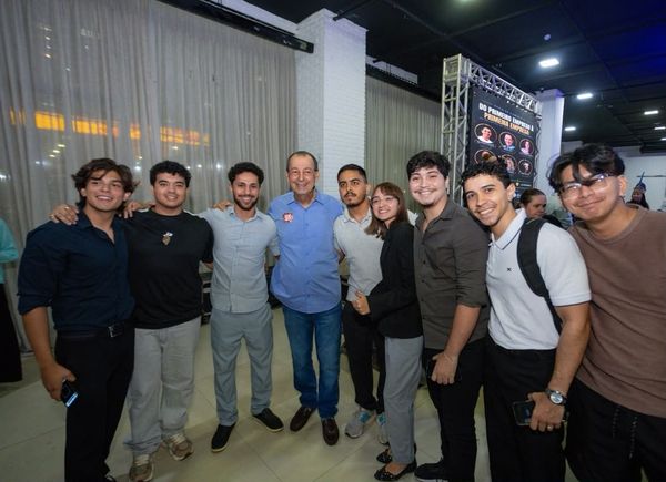 Omar Aziz posa para foto cercado por um grupo de jovens em um evento em ambiente fechado.