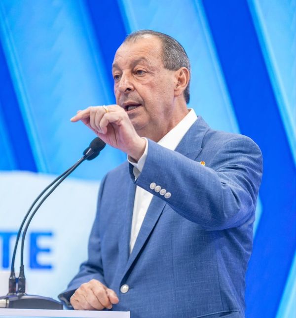 O candidato Omar Aziz, vestindo paletó azul e camisa branca, fala ao microfone durante debate em outubro de 2026.