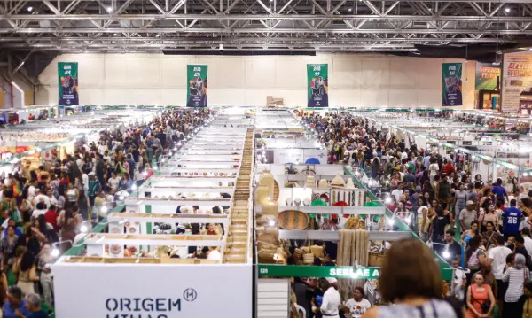 Vista aérea de feira de empreendedorismo com diversos estandes e grande circulação de pessoas em pavilhão de eventos.