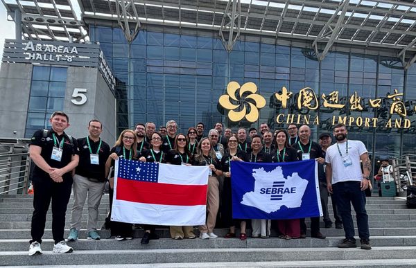 Empresários de Manaus seguram bandeiras do Amazonas e do Sebrae em frente ao pavilhão da Canton Fair, na China.