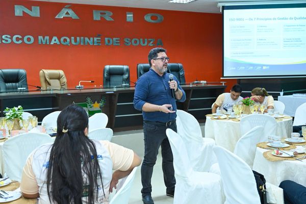 Homem fala ao microfone durante palestra para empresários sentados em mesas redondas no plenário da Câmara de Iranduba.