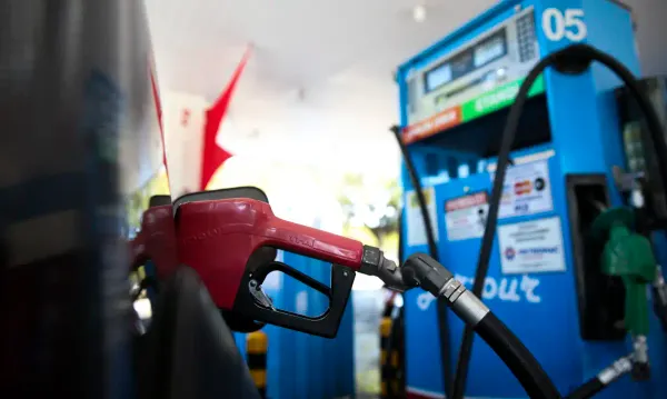 Bico de abastecimento de combustível vermelho inserido em um veículo em um posto de gasolina.