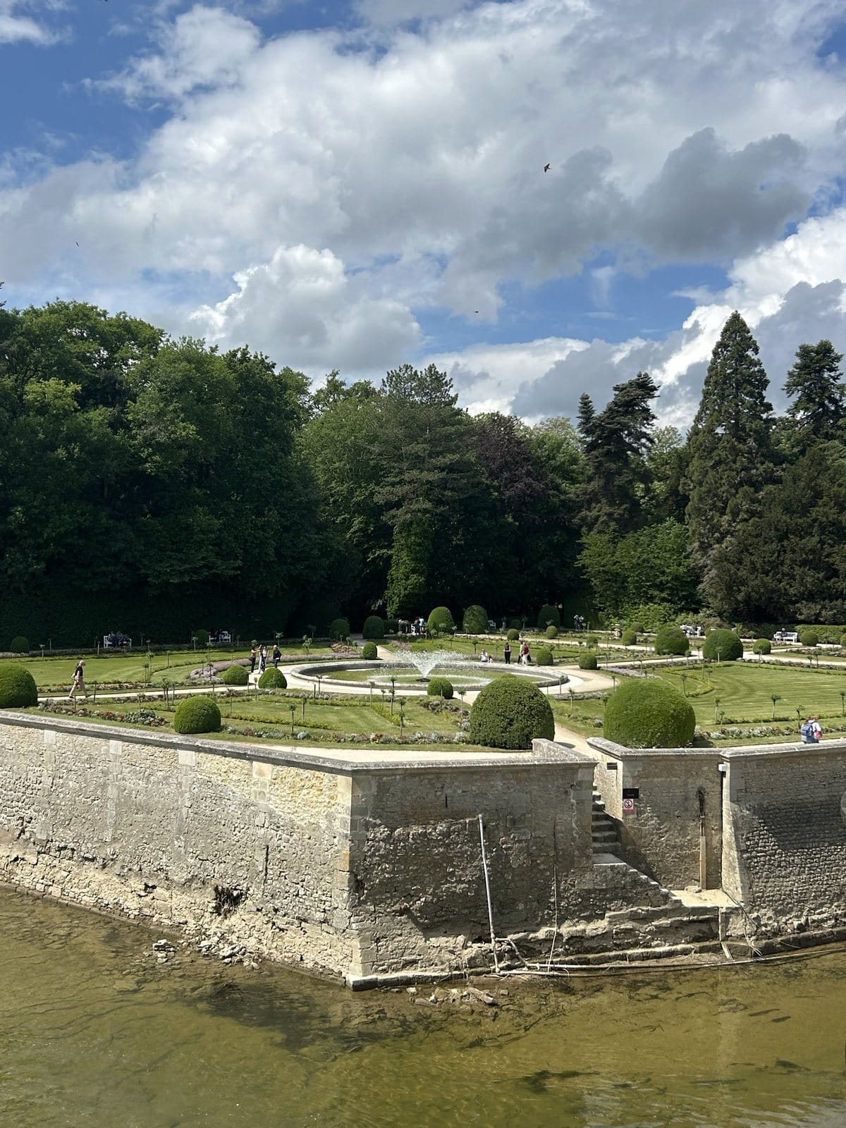The formal gardens of Chenonceau with a fountain, seen from above the water