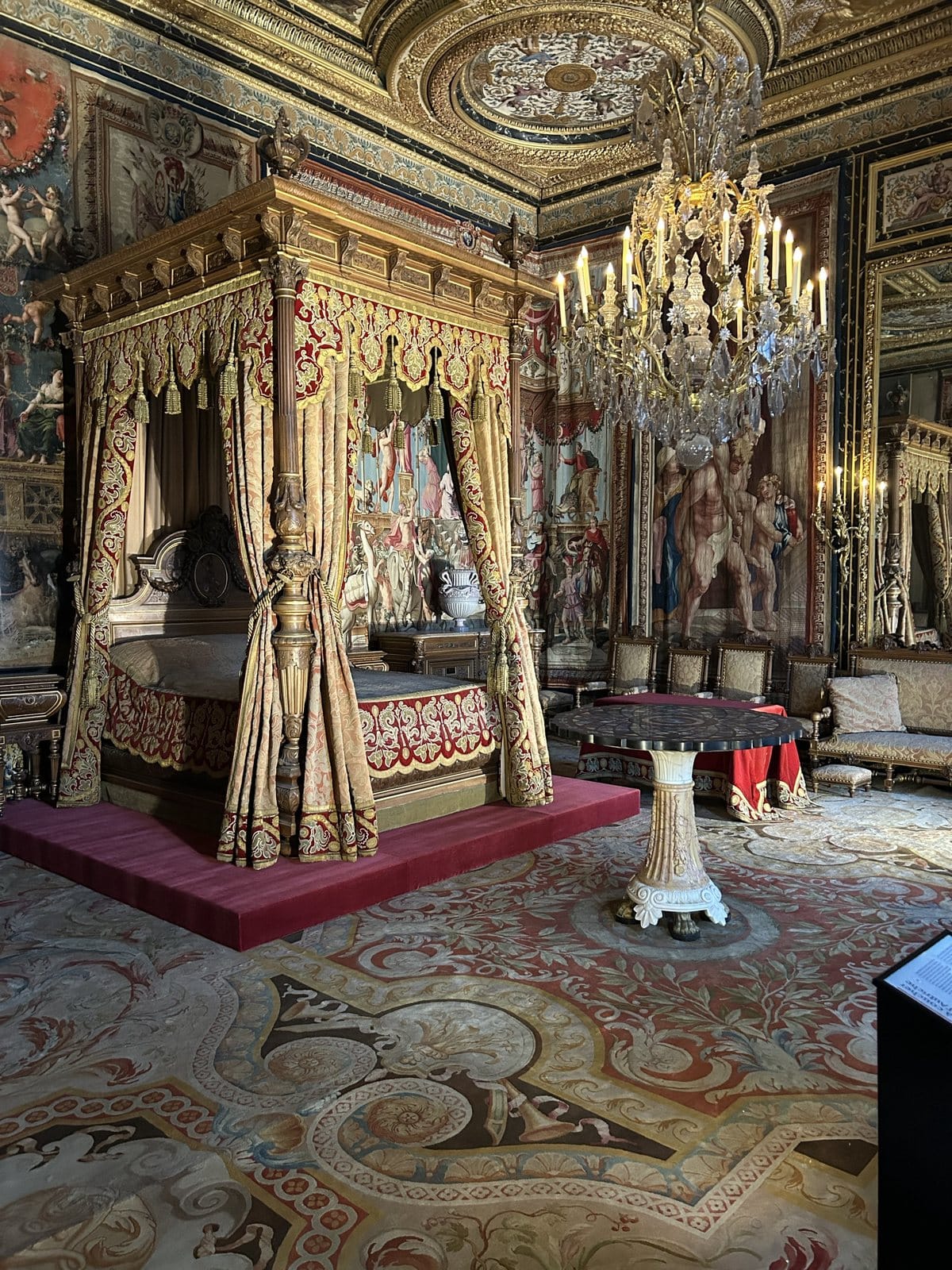  A royal bedroom at Fontainebleau with a canopy bed and a chandelier
