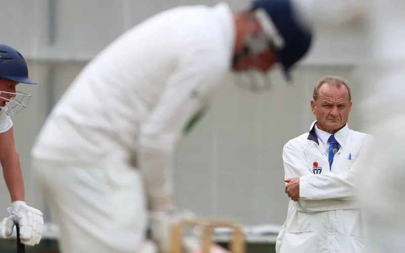 cricket umpire officiates in a halifax cricket league game. View is from wicketkeeper perspective behind the stumps