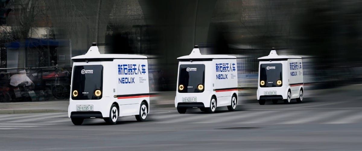 Three white Neolix driverless delivery vans with SF Express branding drive in a line along a city road.