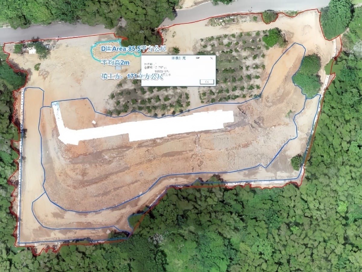 Aerial view of a cleared hillside site with outlined survey areas, surrounded by forest and next to a road.