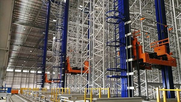 Tall automated stacker cranes running between warehouse storage racks.