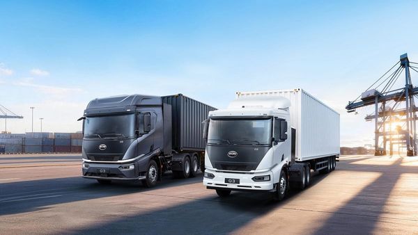 Two BYD Q3 battery-electric heavy trucks hauling a container and a box trailer at a port.